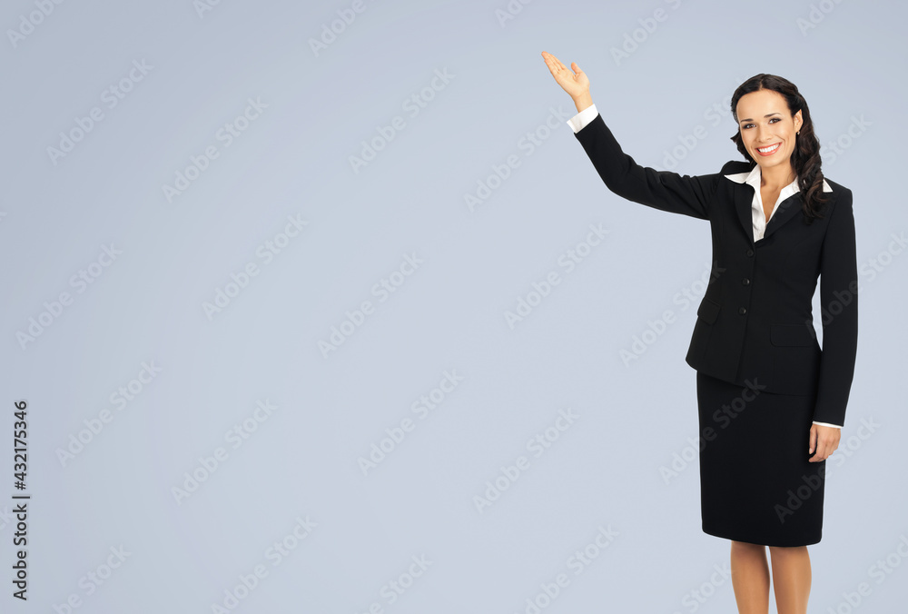 Wall mural Full body of happy smiling attractive woman in black confident suit, showing copy space. Business concept. Isolated over grey background. Brunette businesswoman.