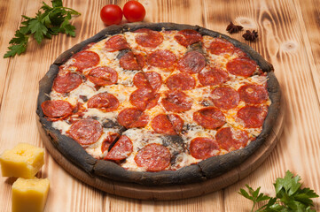 pepperoni pizza on black dough on a wooden Board