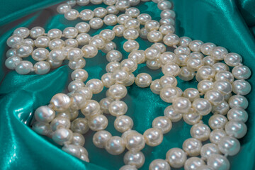 Natural White Pearls in the water on a blue silk texture close-up. Pendants on the neck.