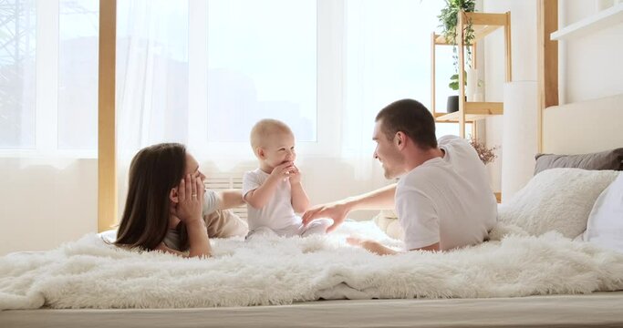 Parents relaxing with playful baby son in bed at home