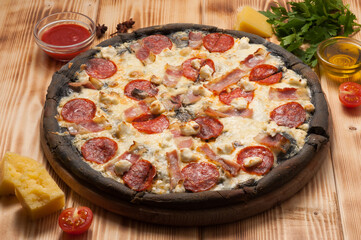 pizza with pepperoni, bacon and mozzarella on the dough black