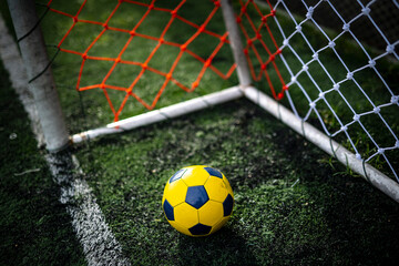Yellow soccer ball behind the goal line after a goal is scored.