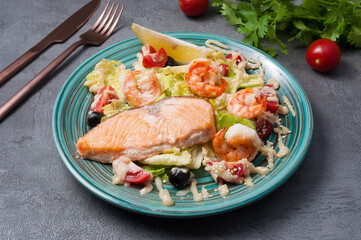 salad with salmon, shrimp and vegetables on a gray background