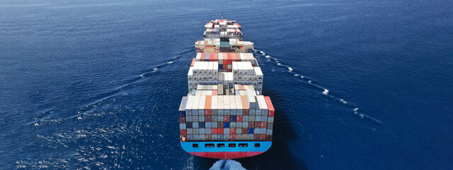 Aerial drone ultra wide photo above huge colourful container carrier vessel cruising deep blue open...