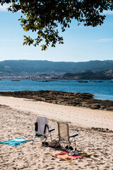 Fototapeta na wymiar Two empty beach chairs and clothes, on the beach of Samieira in the Rias Baixas, Galicia (Spain)
