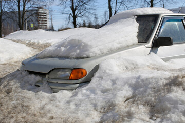 Car covered with a thick snow layer after heavy snowfall. 
Spring, the snow is melting.