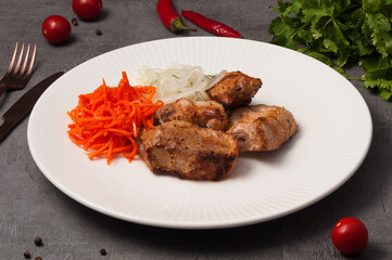 pork skewers on a white plate with onions and carrots