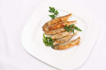 Fried crispy capelin on a white plate