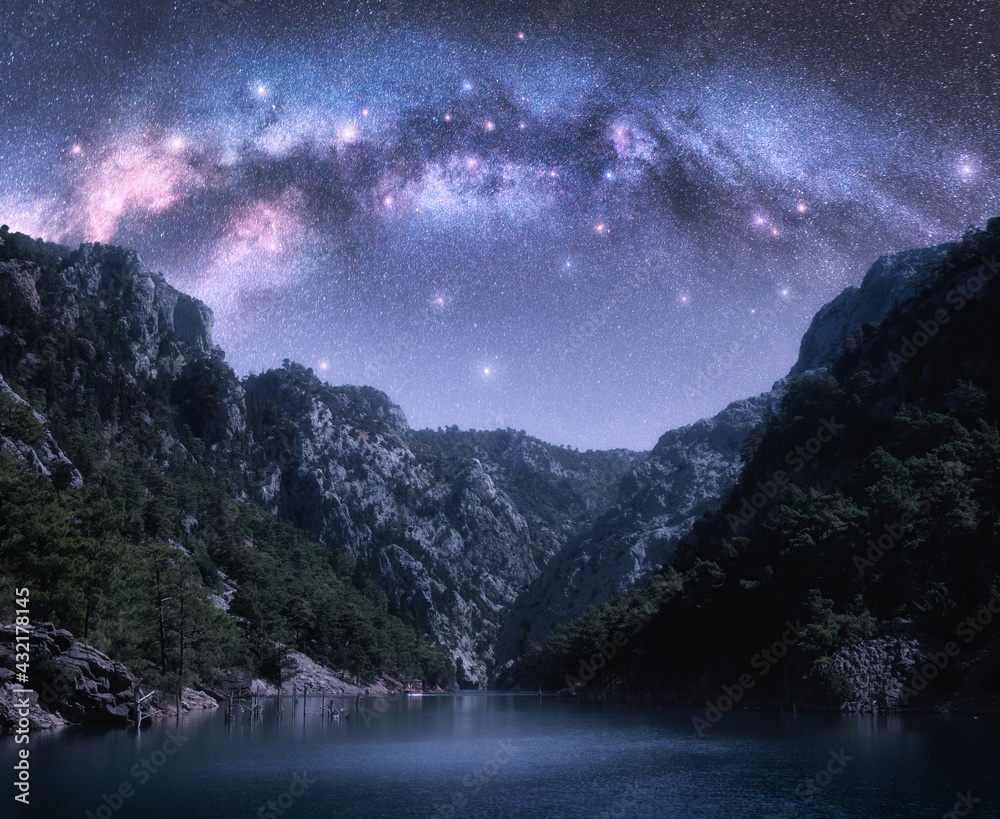 Wall mural arched milky way and stars over beautiful mountains and sea at night in summer. colorful landscape w