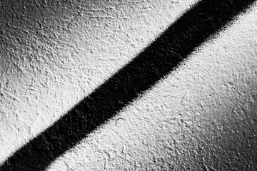 Rough white wall with black diagonal line. Close up view