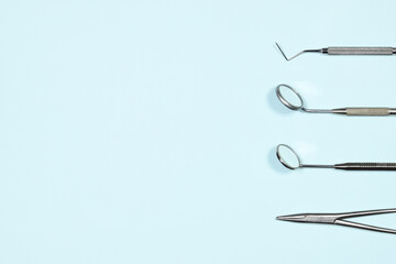 Medical dental instruments on light blue background with copy space. Flat lay closeup top view on dental equipment. Dental mirrors, probes, forcepts