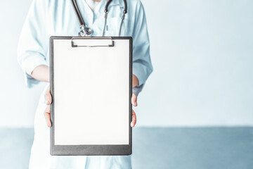 Female doctor with stethoscope holding clipboard in the hospital.