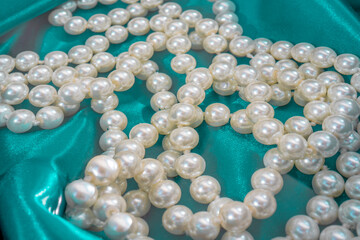 Natural White Pearls in the water on a blue silk texture close-up. Pendants on the neck.