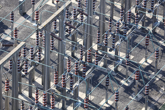 An aerial view taken from a helicopter of a high voltage power distribution substation in Britain. The DNO site has many insulator posts, bus bars and switches all seen from an elevated perspective.