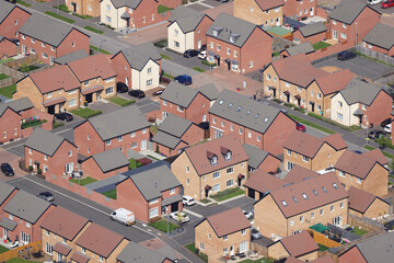 An aerial view taken from a helicopter of a large new housing estate in South Wales, UK. Many similar houses in a dense development. Homes forming a repetitive isometric pattern.
