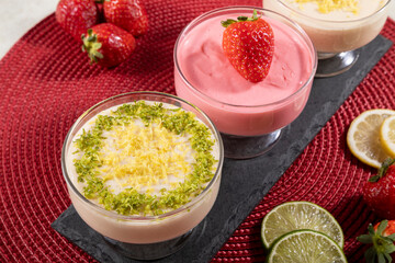Delicious lemon and strawberry mousses in glass jars on top of black stone