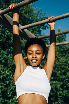 Female athlete looking down while hanging on monkey bar in park