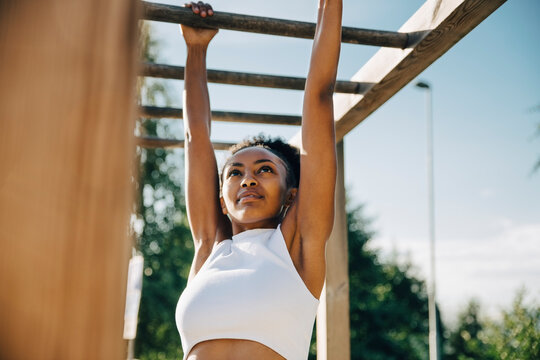 Female athlete hanging on monkey bar in park