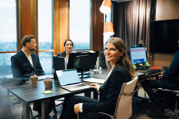 Portrait of female lawyer sitting with colleagues during meeting in office