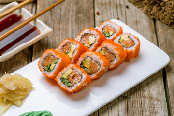 California roll with salmon on white plate on old wooden table