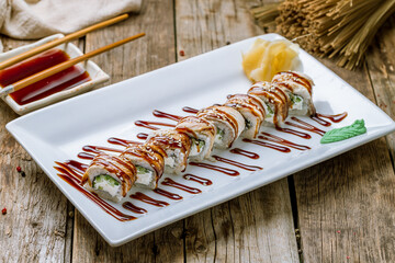 roll with eel, cream cheese and cucumber on white plate on old wooden table © bbivirys