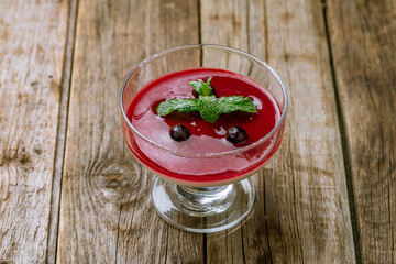 Panna cotta with berry sauce with mint on old wooden table