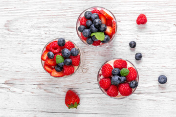 Fototapeta na wymiar Muesli with yogurt and berries in a glass On a wooden table. Dessert preparation process. Fitness food. Copy space. High quality photo