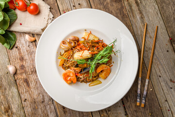 Udon noodles with seafood top view on old wooden table