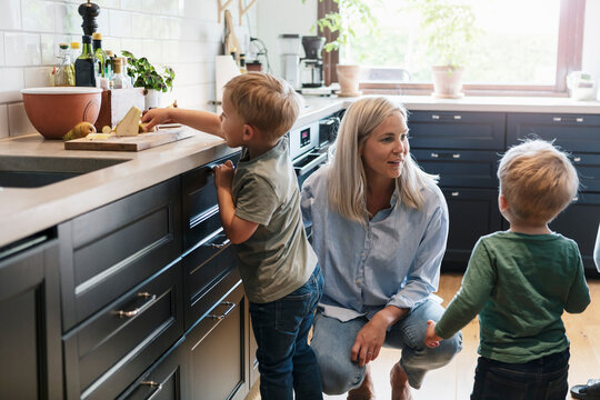 Elder son taking pear while mother talking with younger sibling in kitchen
