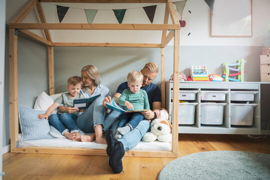Parents with children reading book in bedroom