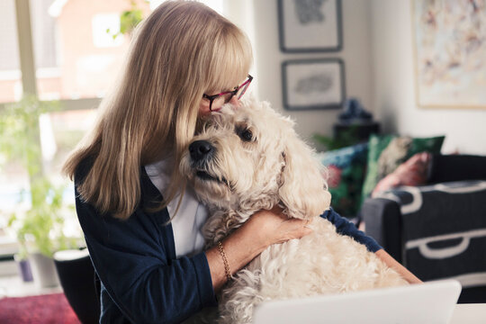 Blond woman kissing and embracing dog at home