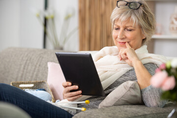 happy elderly female browsing social media on tablet