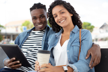 loving couple on a bench having fun with tablet