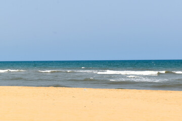 A beach with light blue sky , white sand and blue water