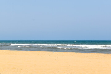 Fototapeta na wymiar A beach with light blue sky , white sand and blue water