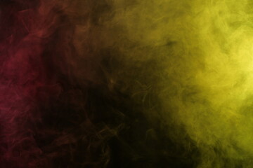 Obraz na płótnie Canvas Artificial smoke in red-yellow light on black background