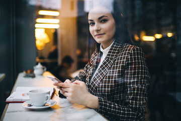Calm female browsing smartphone in cafeteria