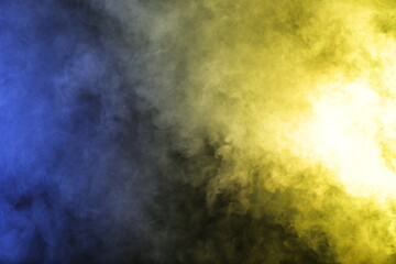 Artificial smoke in blue yellow light on black background