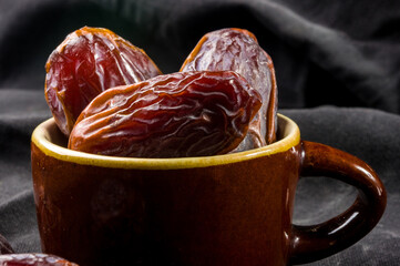 Big luxury dried date fruit in bowls on the dark surface, kurma ramadan kareem concept, close up.