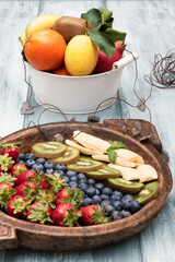 Fresh and various fruits isolated in a shabby chic background. Lemon kiwi banana strawberry blackberry. Vertical