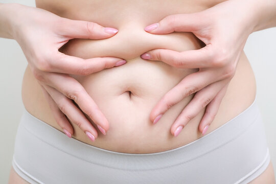 Fat belly of a woman. female hand of excessive fat on the belly.