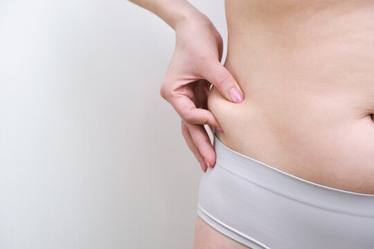 Fat belly of a woman. female hand of excessive fat on the belly.