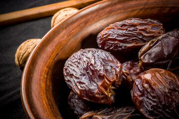 Big luxury dried date fruit in bowls on the dark surface, kurma ramadan kareem concept, close up.
