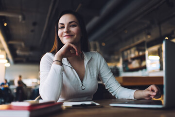 Positive woman working on laptop in cafeteria