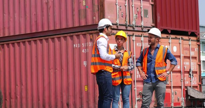 Hispanic man harbor worker talking on the walkie-talkie radio and control loading containers at container warehouse. container yard port of import and export goods