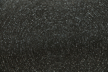 Abstract background of shiny rings of gray, black and beige colors with iridescent glitter.