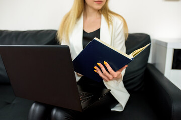 Remote work.Entrepreneur woman wearing white jacket working with a laptop sitting on couch at home.Online consultation of a tax lawyer, accountant in the office