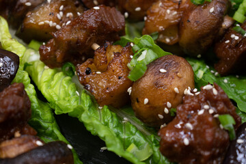 Vegan seitan, mushroom and eggplant skewers on lettuce leaves on slate board along with sides