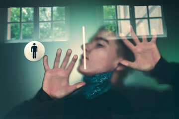 young man with corona protective mask presses himself against a window
