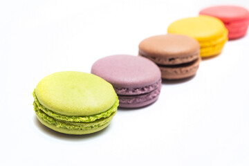 Various flavors of pastel macarons stacked against isolated on white background. Macarons is a delicate meringue-based cookie sandwich It is a dessert of French origin.